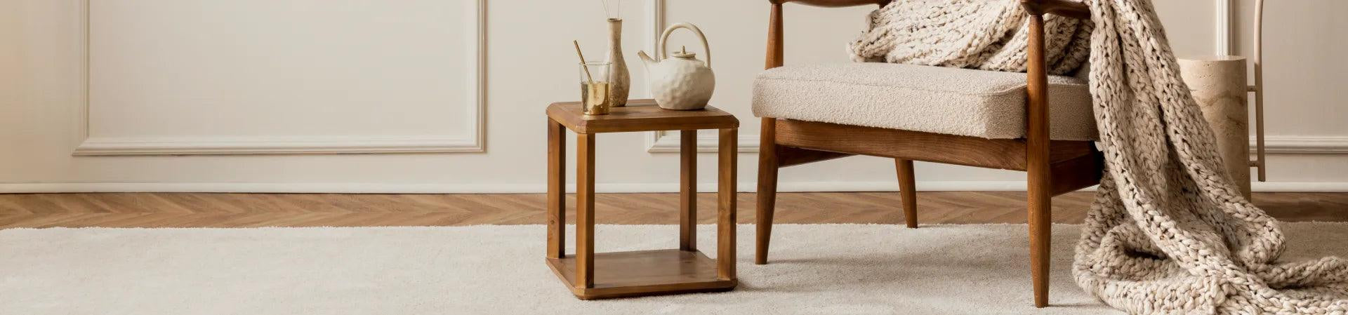 Best selling teak furniture including a wooden armchair and side table with cozy knitted blanket in a stylish living room