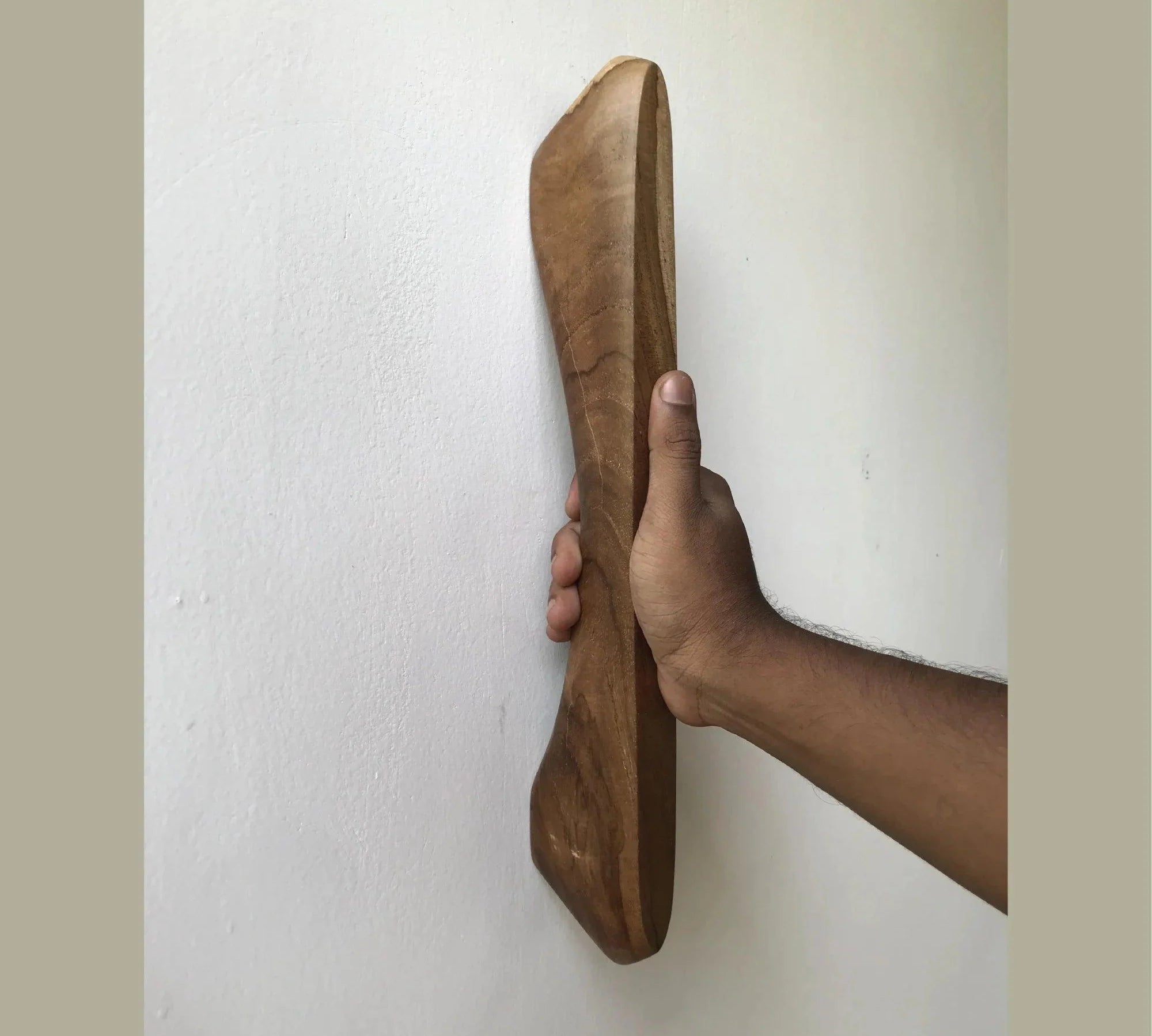 Hand holding wooden Front Door Handle Hardware by Wood Ceylon mounted on a white wall
