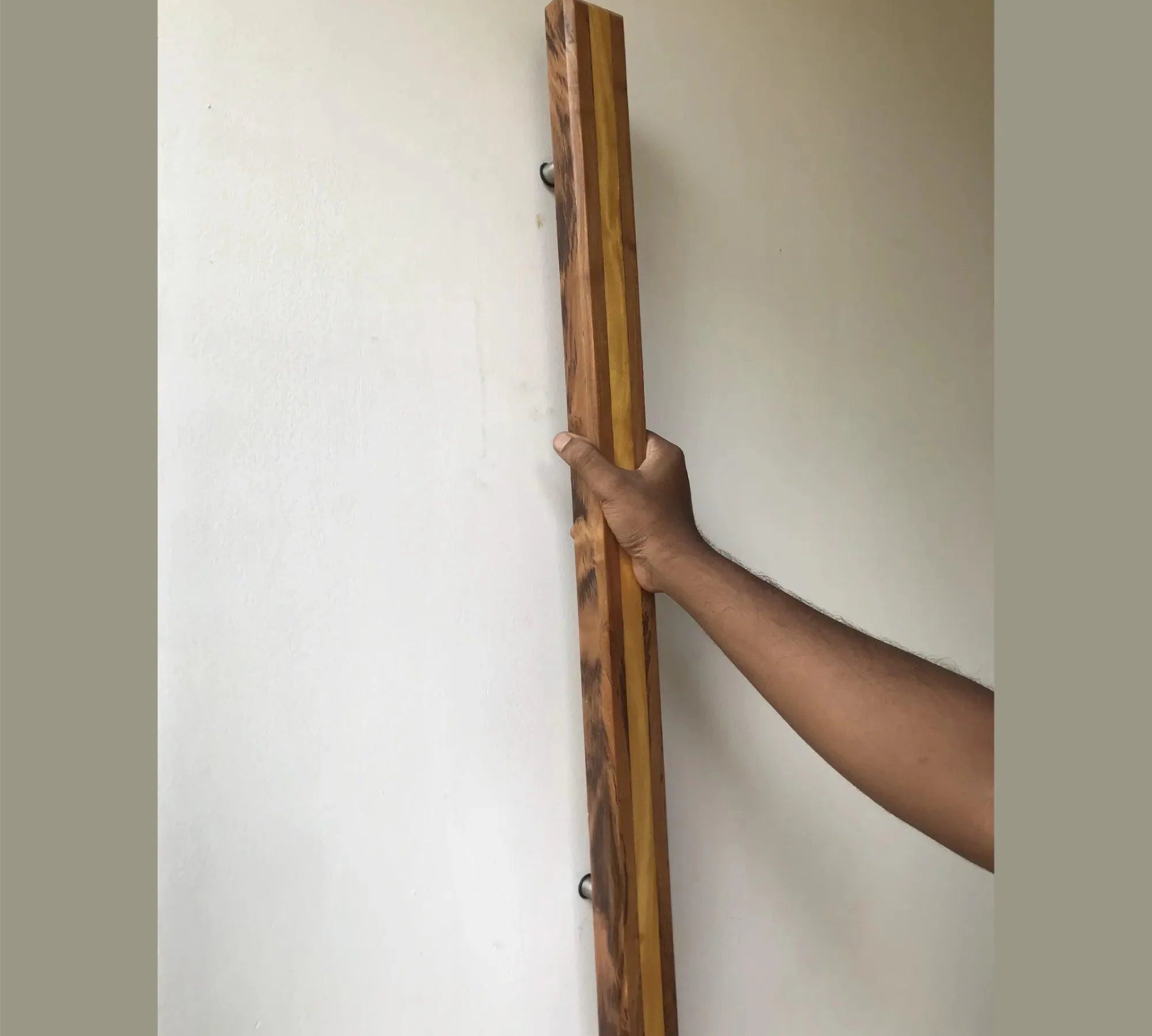 Hand holding a large wooden door handle made from mixed wood tones by Wood Ceylon