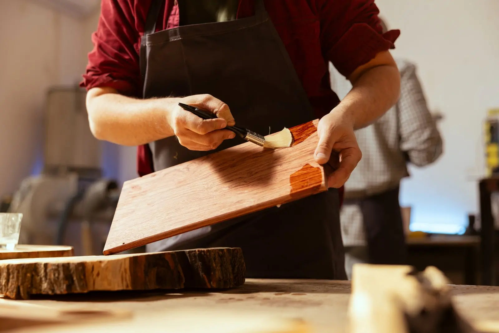 Worker in workshop applying Furniture & Wood Polish with brush to wooden panel to restore shine