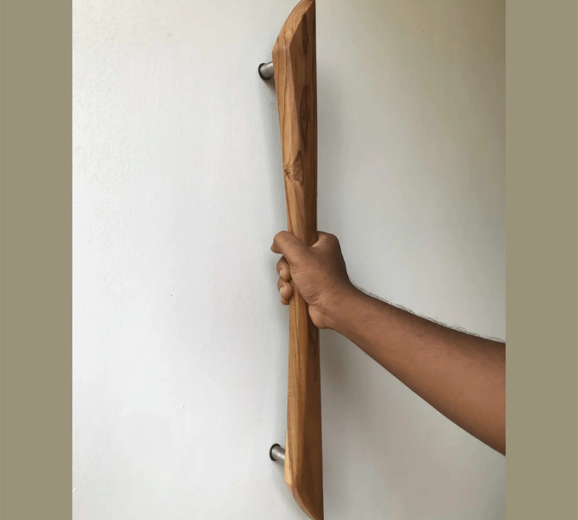 Hand holding a wooden door handle installed on white wall featuring Handmade Barn Door Handles