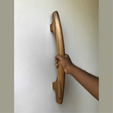 Hand holding a handmade teak door handle mounted on a white wall by Wood Ceylon